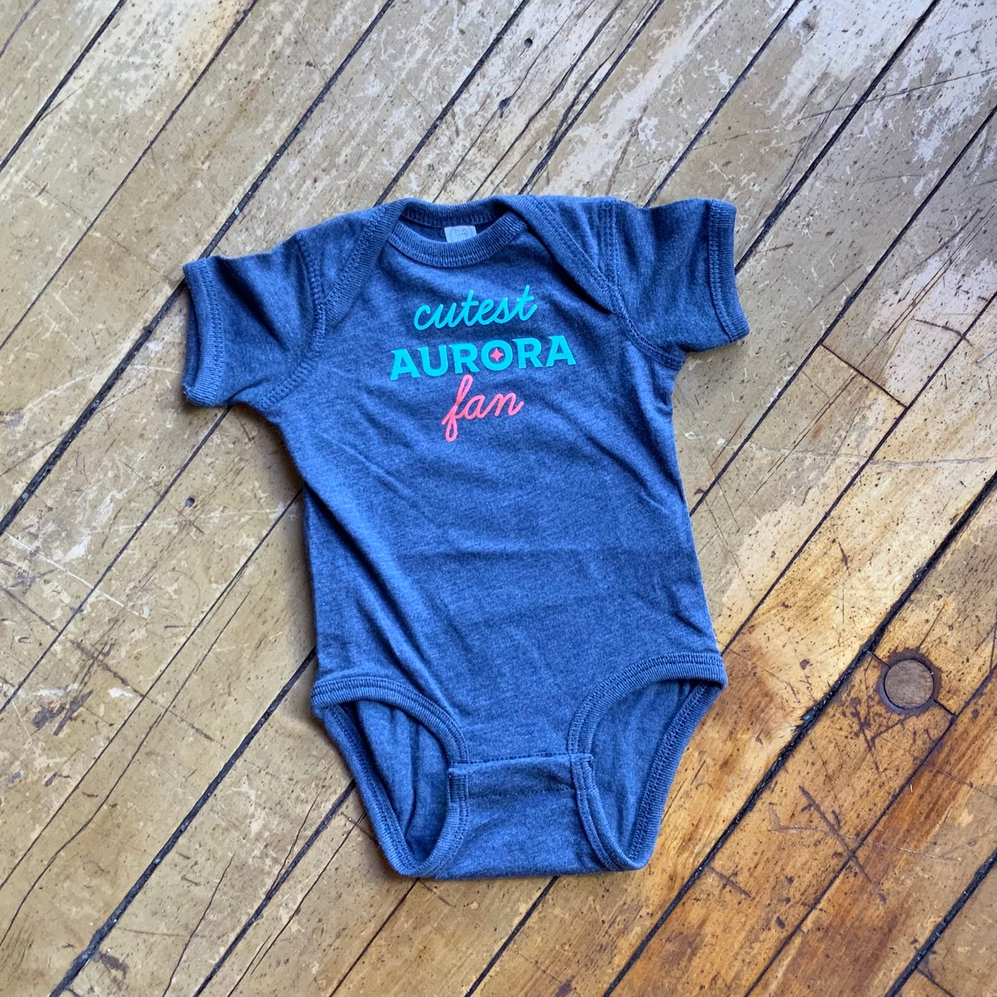 Grey onesie with the words "Cutest Aurora Fan" in teal and orange