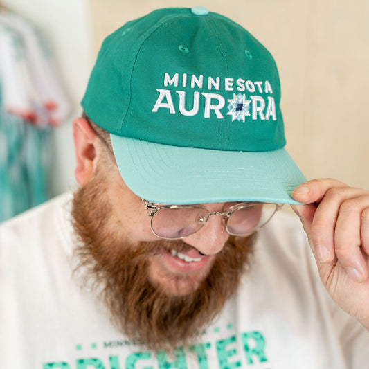 Teal hat featuring the words "Minnesota Aurora" embroidered in white, with the "O" in Aurora being replaced with a quilted star shape