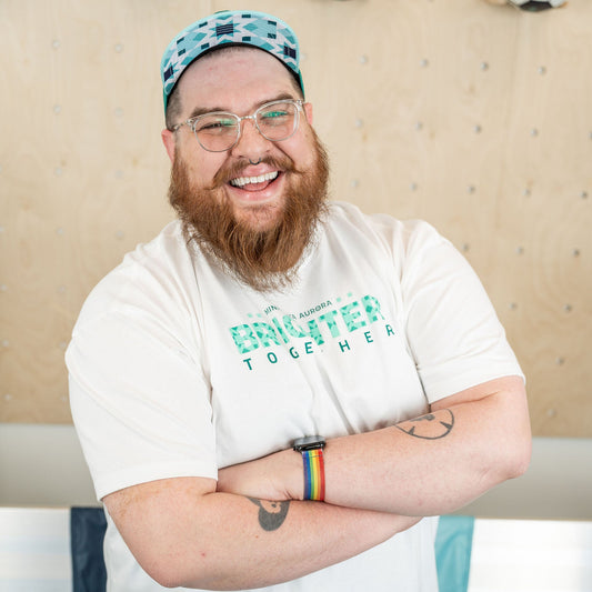 White short-sleeved shirt with the words "Brighter Together" filled in with a teal geometric star pattern