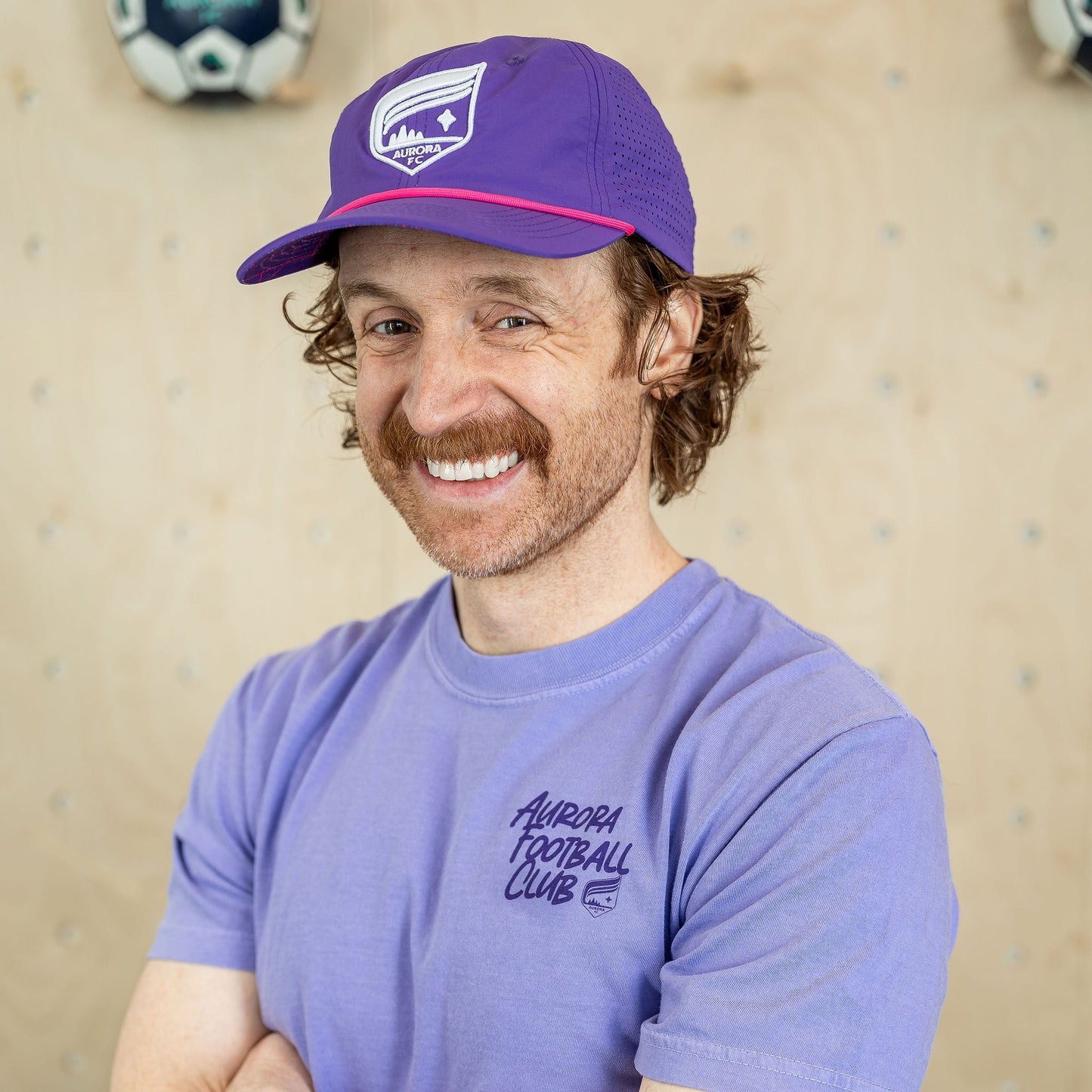 Light purple short-sleeved shirt with the words "Aurora Football Club" and the Aurora crest in dark purple