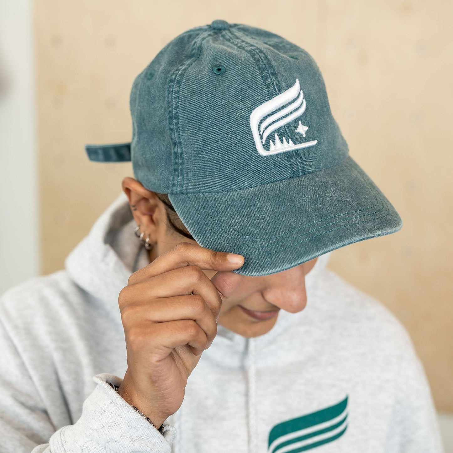 Teal hat with the Aurora crest embroidered in white