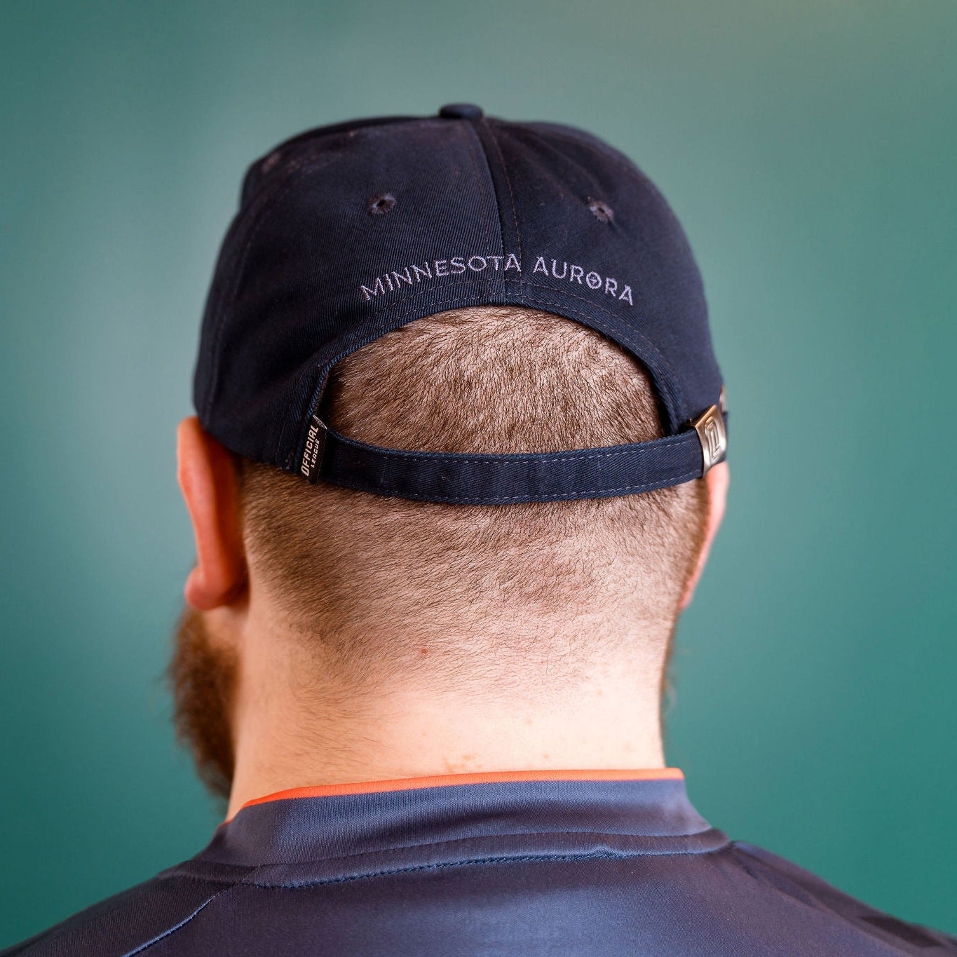 Person wearing a navy blue cap with 'Minnesota Aurora' text on a teal background