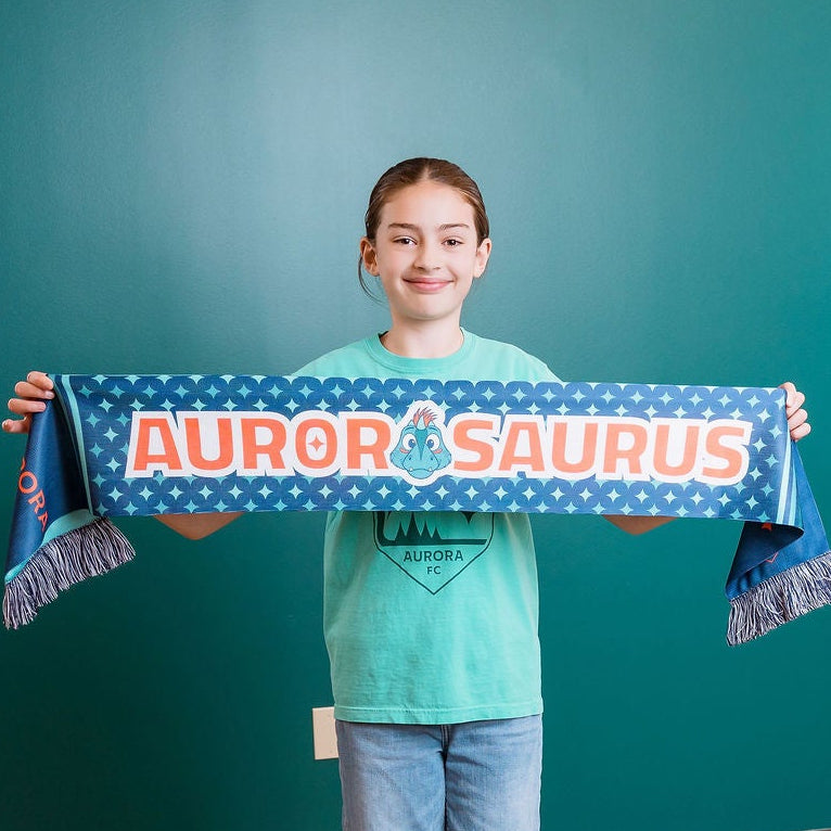 Person holding a 'Aurorasaurus' scarf in a photo studio setting
