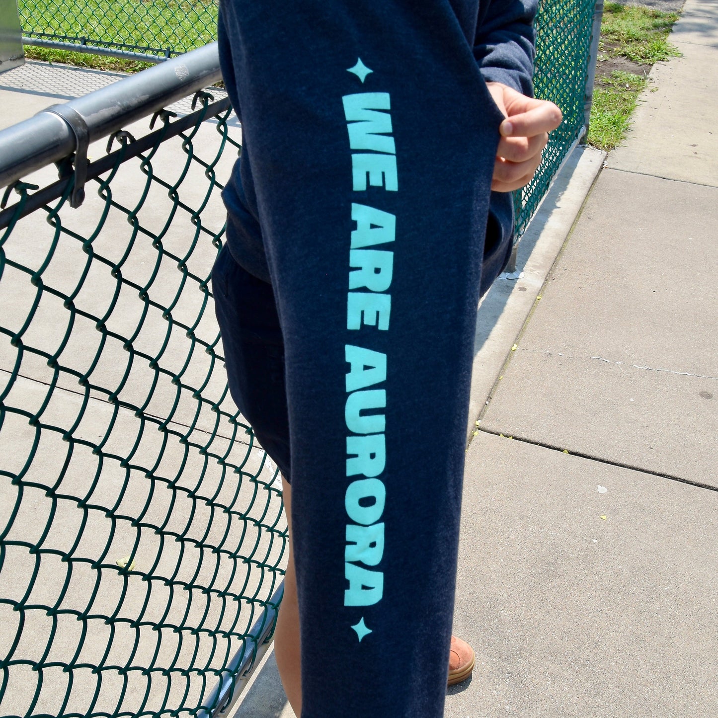Person wearing navy sweatshirt with 'WE ARE AURORA' text.