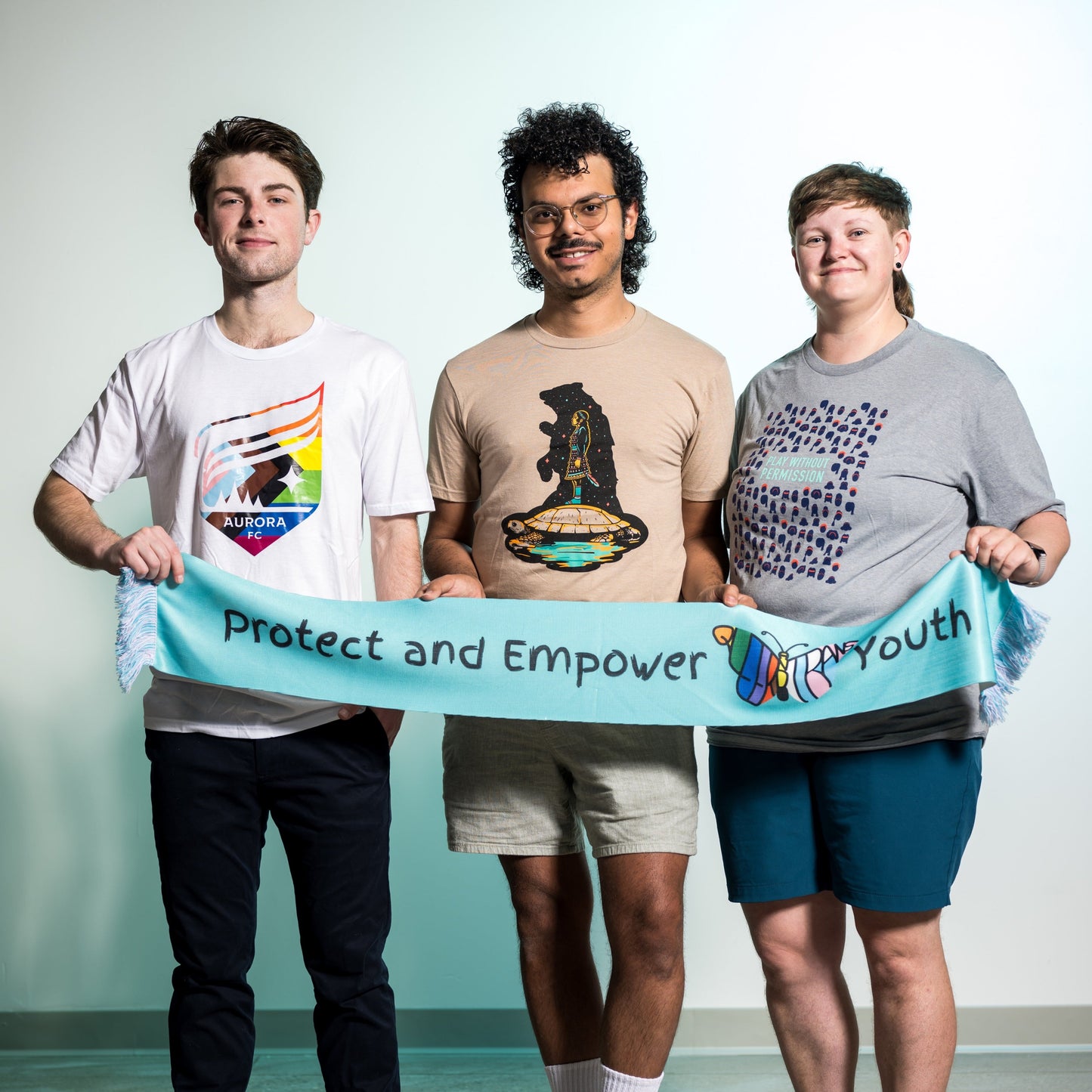 Teal scarf with the words "Protect and Empower Youth" featuring a butterfly that has the words "Queer and Trans"