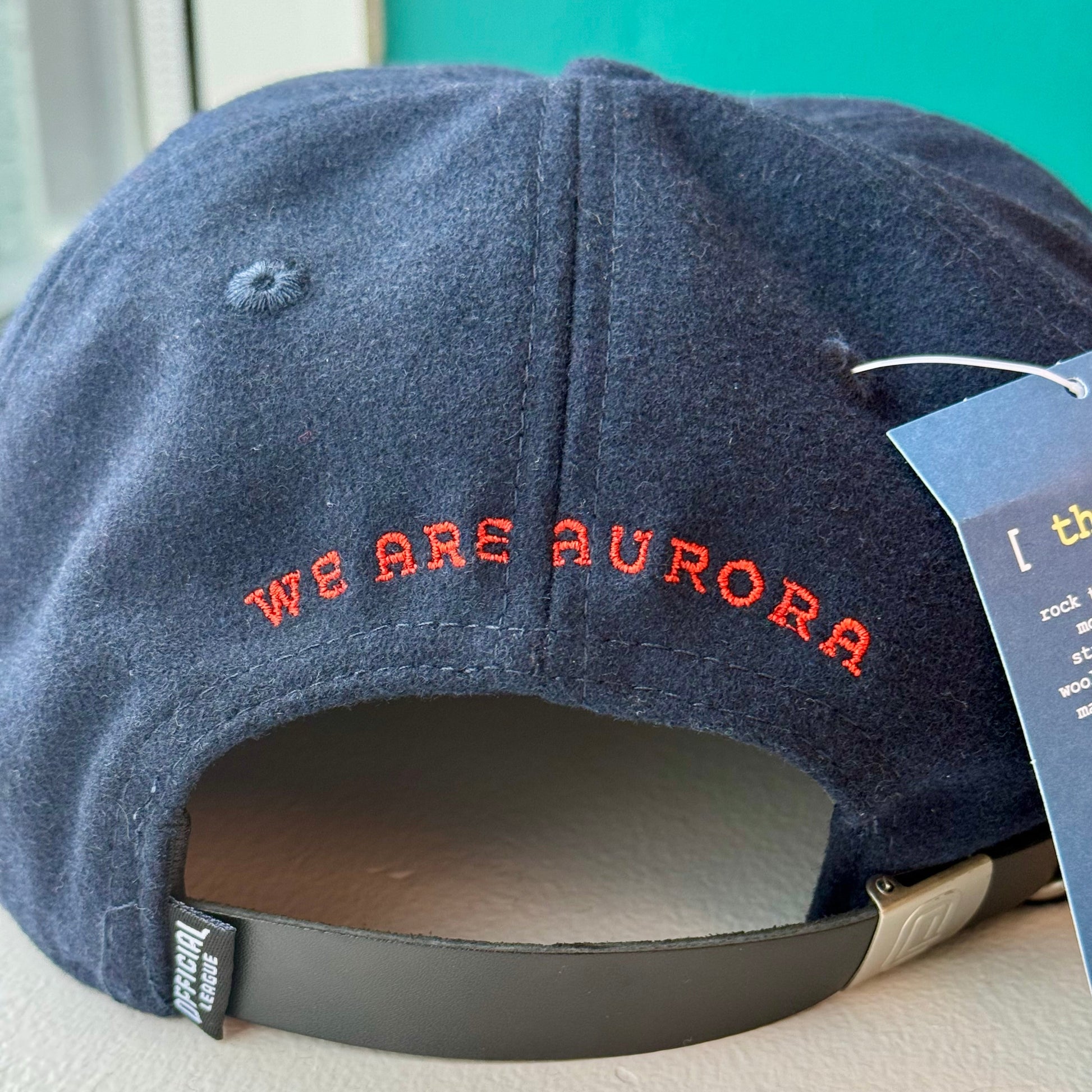 Blue cap with 'WE ARE AURORA' text on a white surface