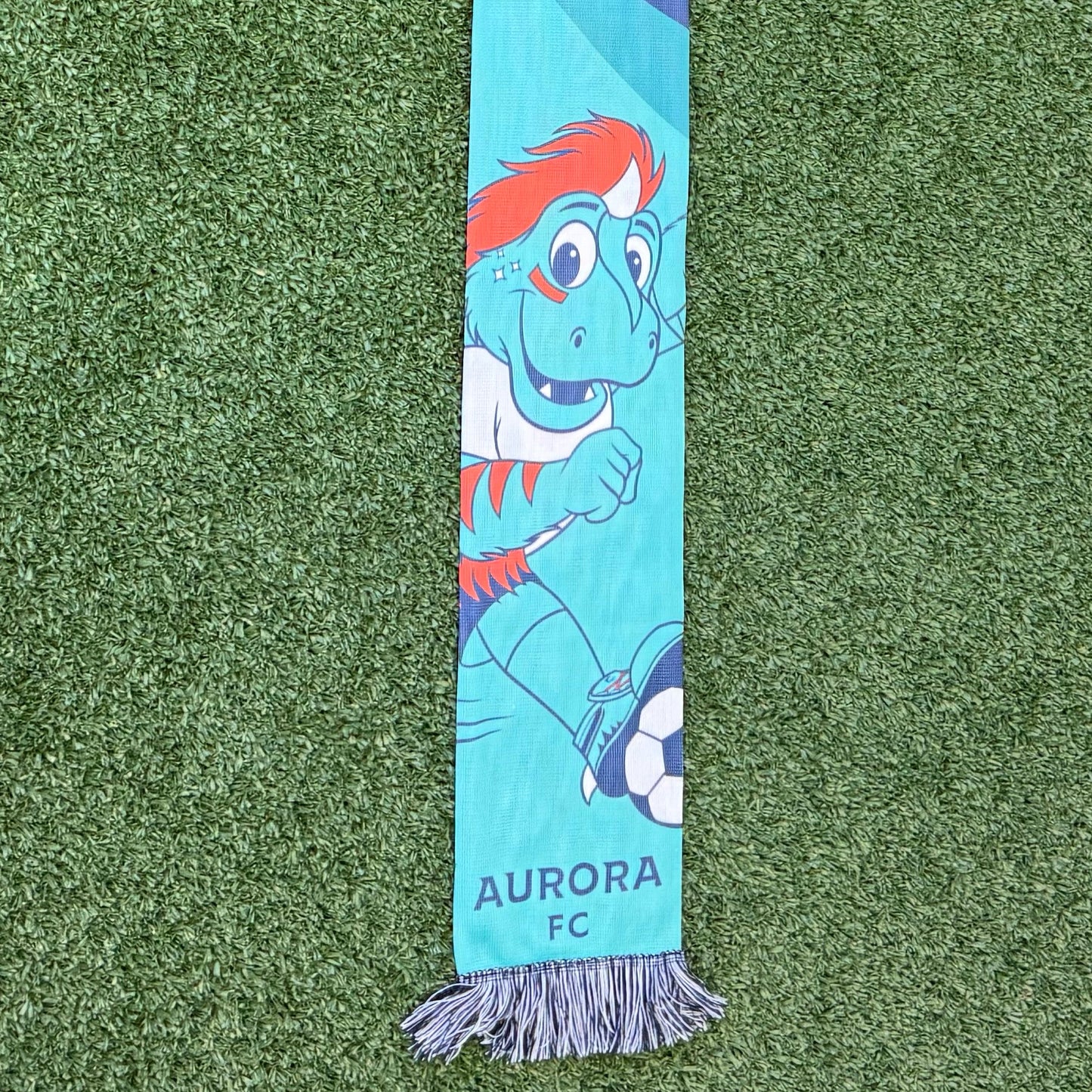 Scarf with 'Rory' printed on it on a green surface