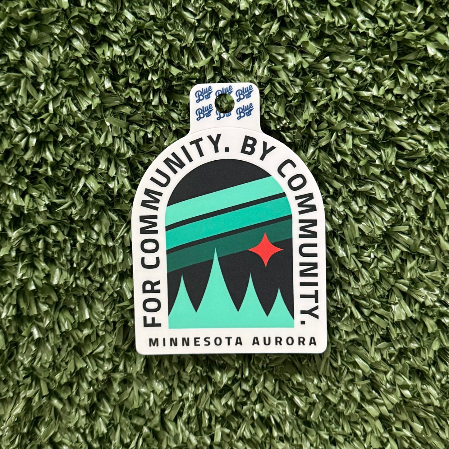 Sticker with 'For Community, By Community, Minnesota Aurora' text on a green textured background