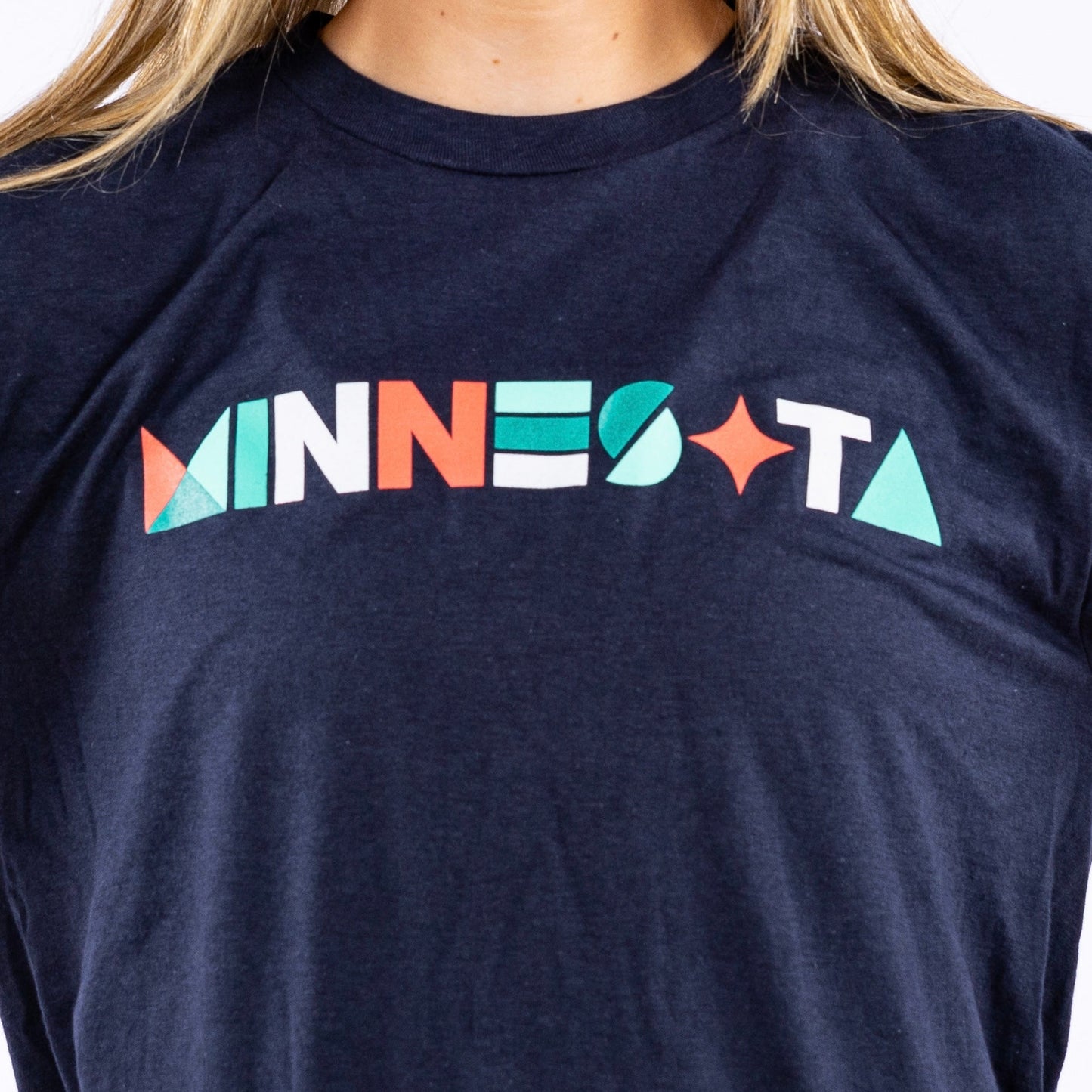 Navy blue short-sleeved shirt with the word "Minnesota" written in different geometric shapes in the colors orange, white, and teal