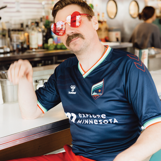 Navy soccer jersey with orange, white, and teal around the collar and the sleeves