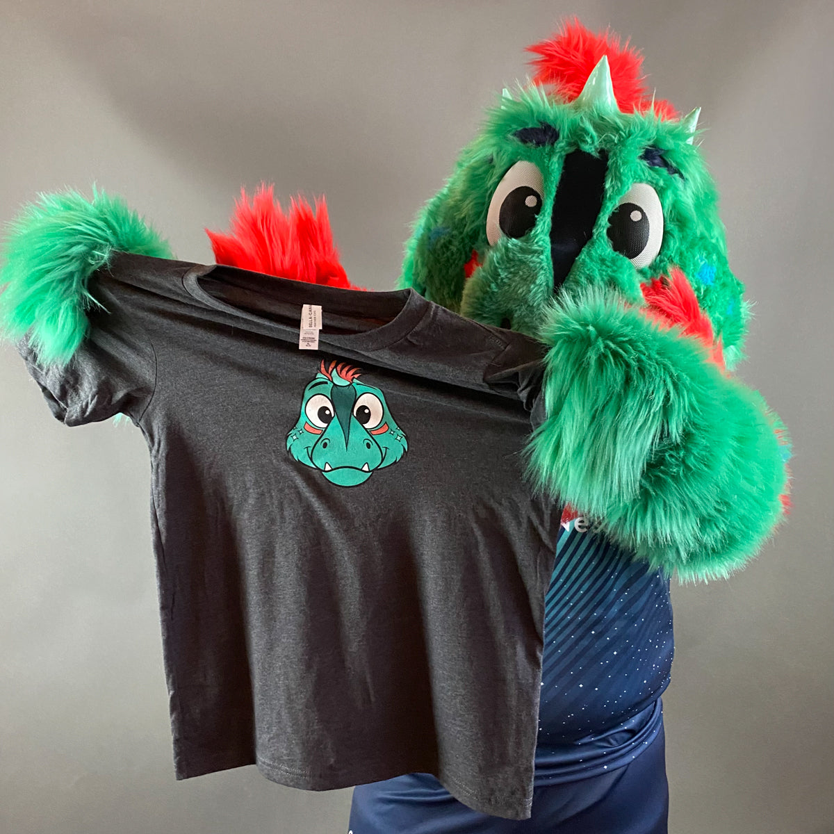 Dark grey short-sleeved shirt adorned with the face of the Aurora mascot, Rory the Aurorasaurus