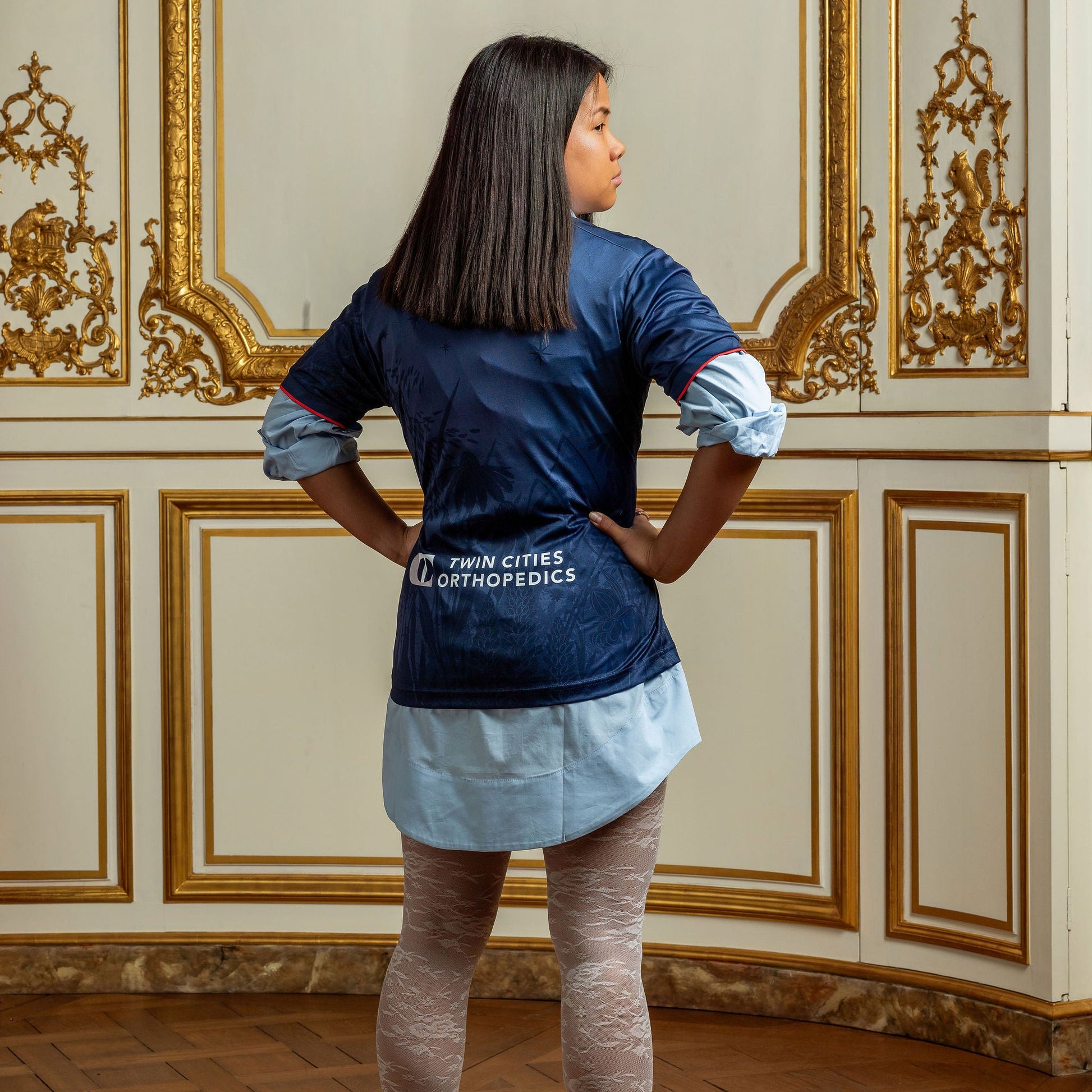 Person wearing a navy jersey with white text in an ornate room.