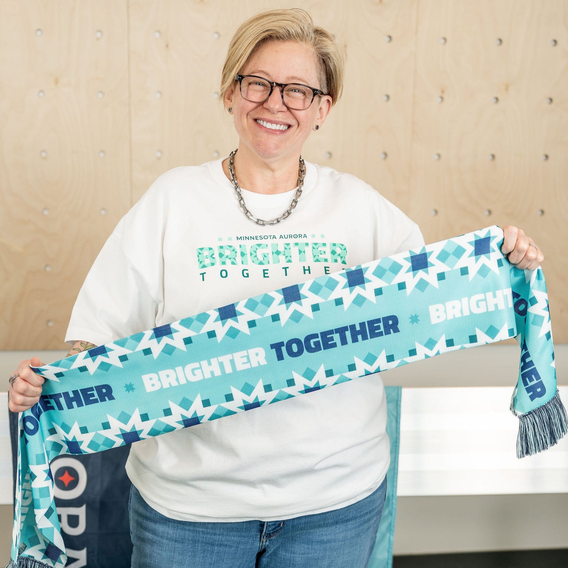 Teal scarf with the words "Brighter Together" in white and navy blue, surrounded by a geometric pattern