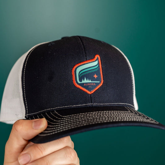 Navy blue hat with a white mesh back featuring the Aurora crest outlined in orange