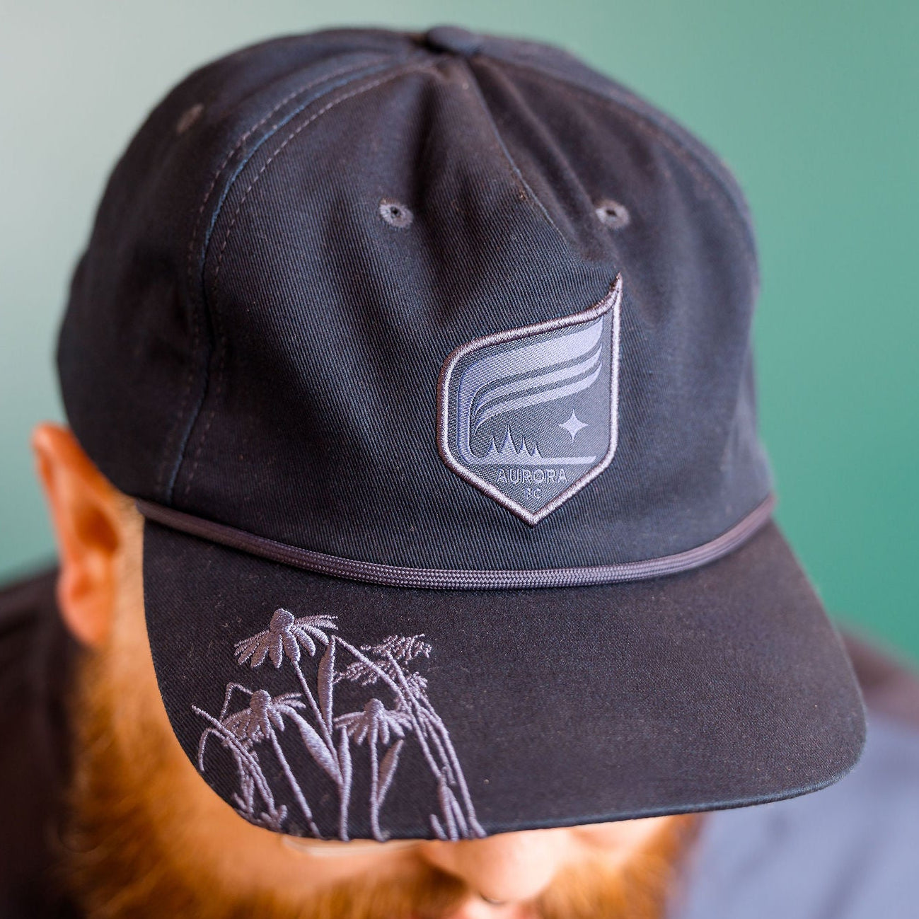 Navy cap with a logo worn by a person against a green background