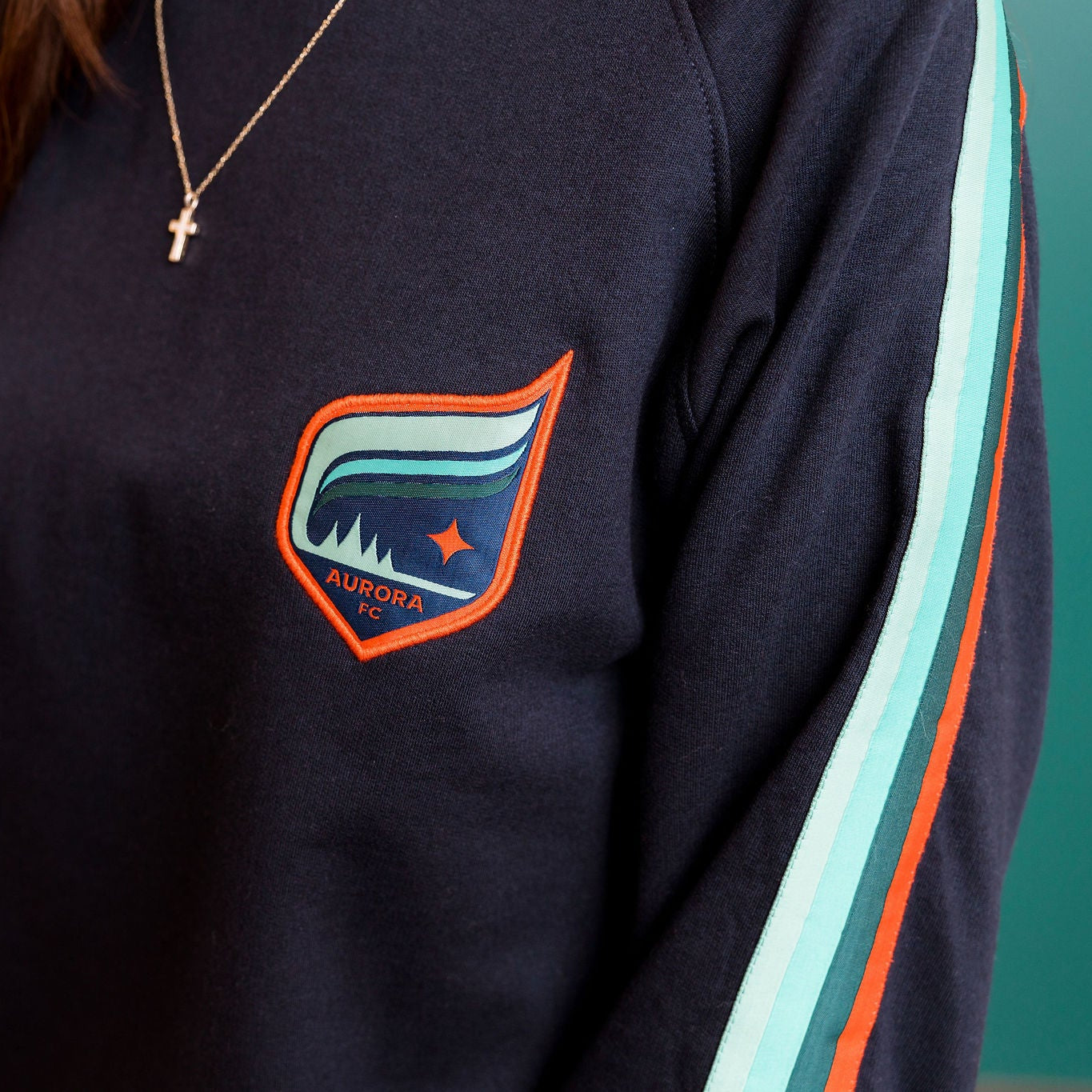Navy sweatshirt with a colorful logo on a teal background