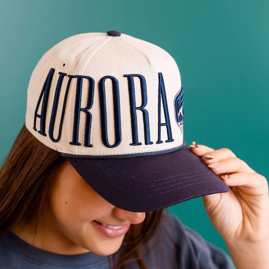 Person wearing a cap with 'Aurora' text against a teal background