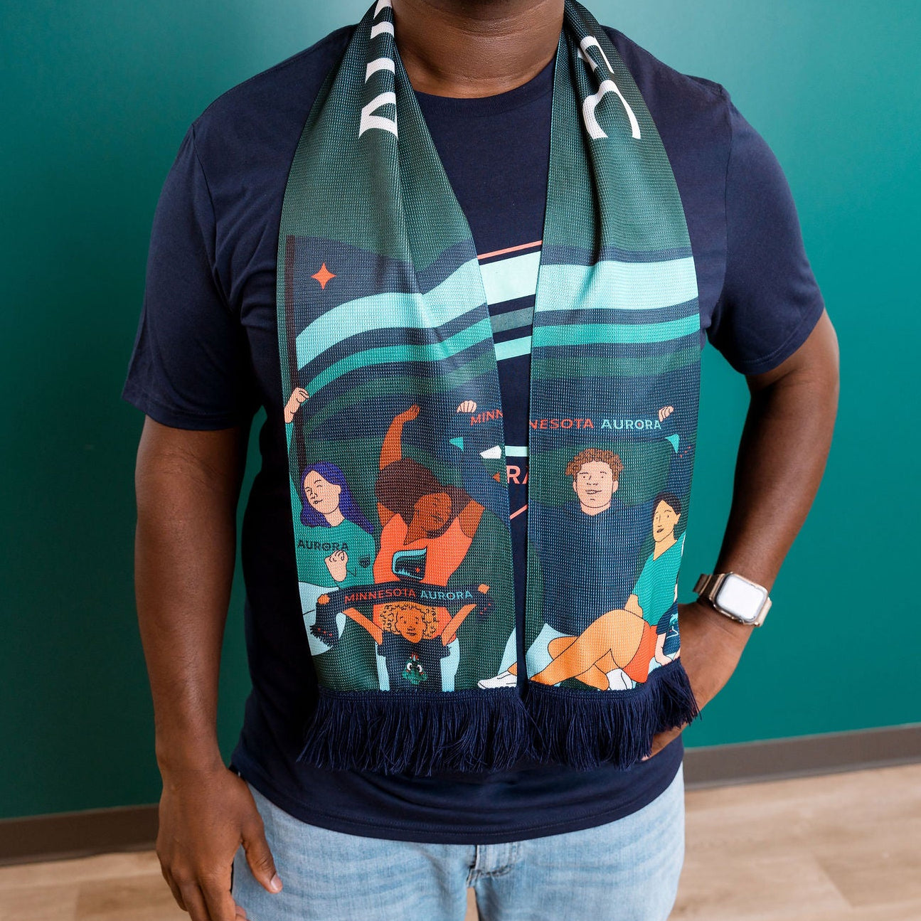 Person wearing a colorful scarf with character designs against a teal wall.