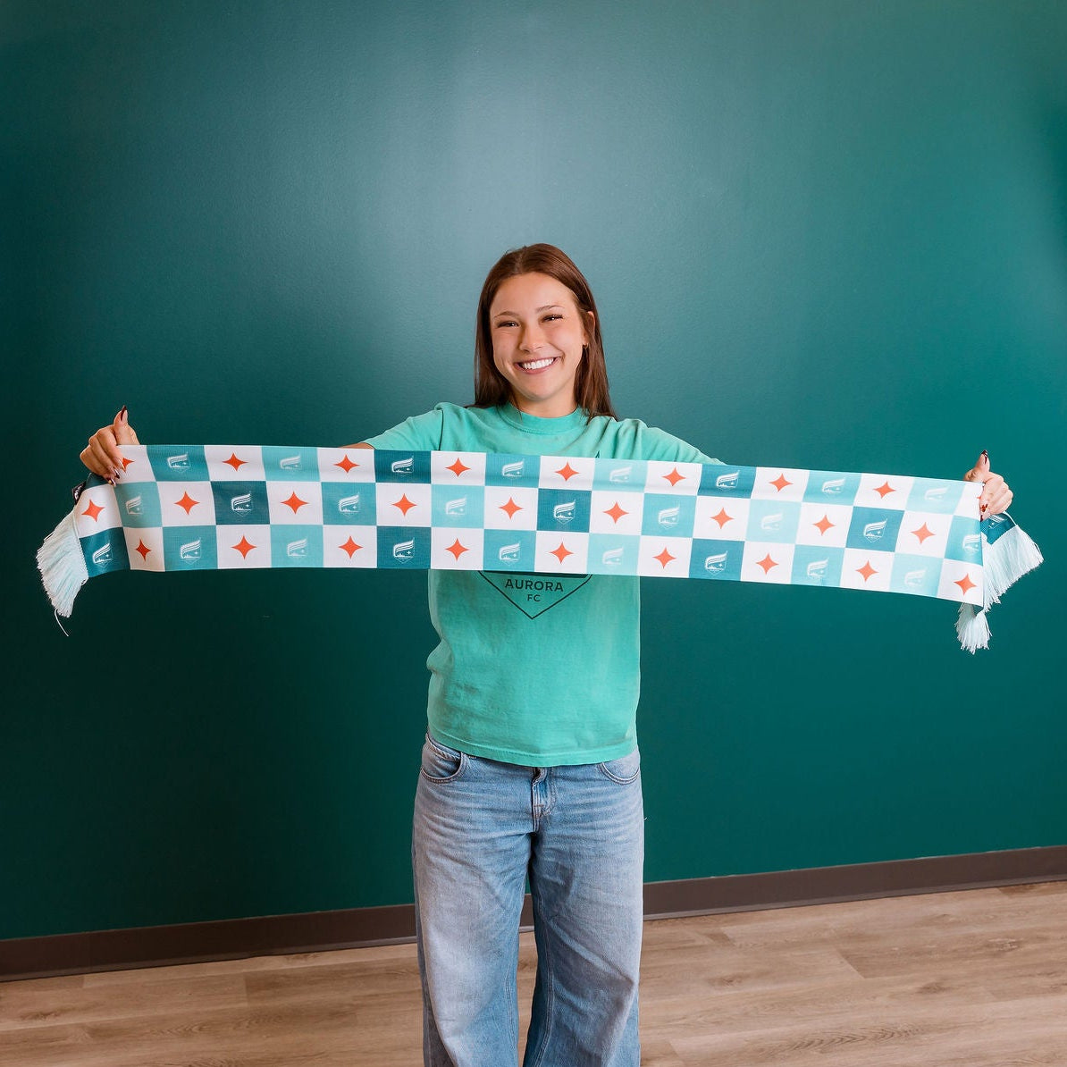 Person holding a patterned scarf in front of a teal wall