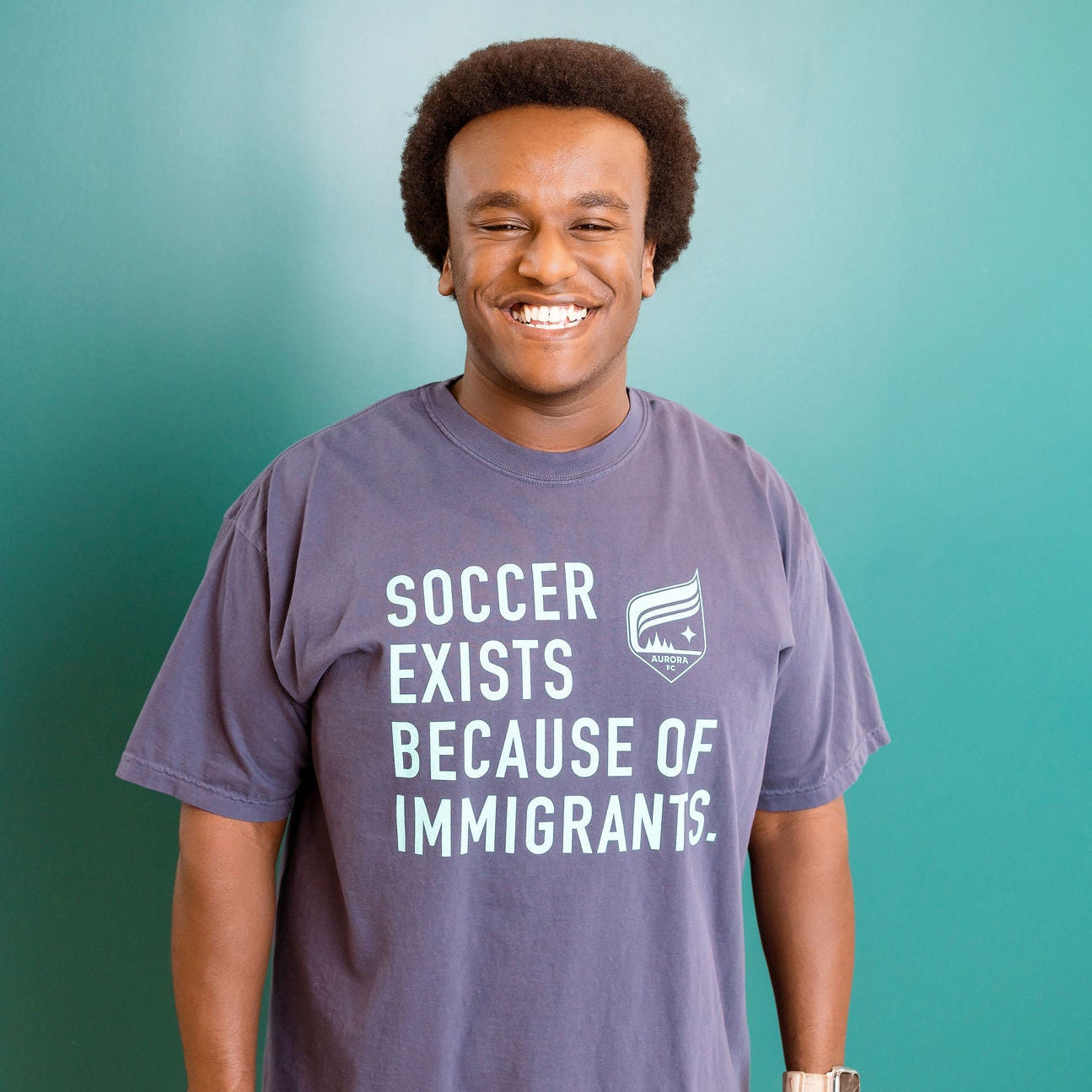 Person wearing a t-shirt with a message on a teal background