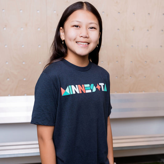Person wearing a navy t-shirt with 'MINNESOTA' printed on it, standing indoors.