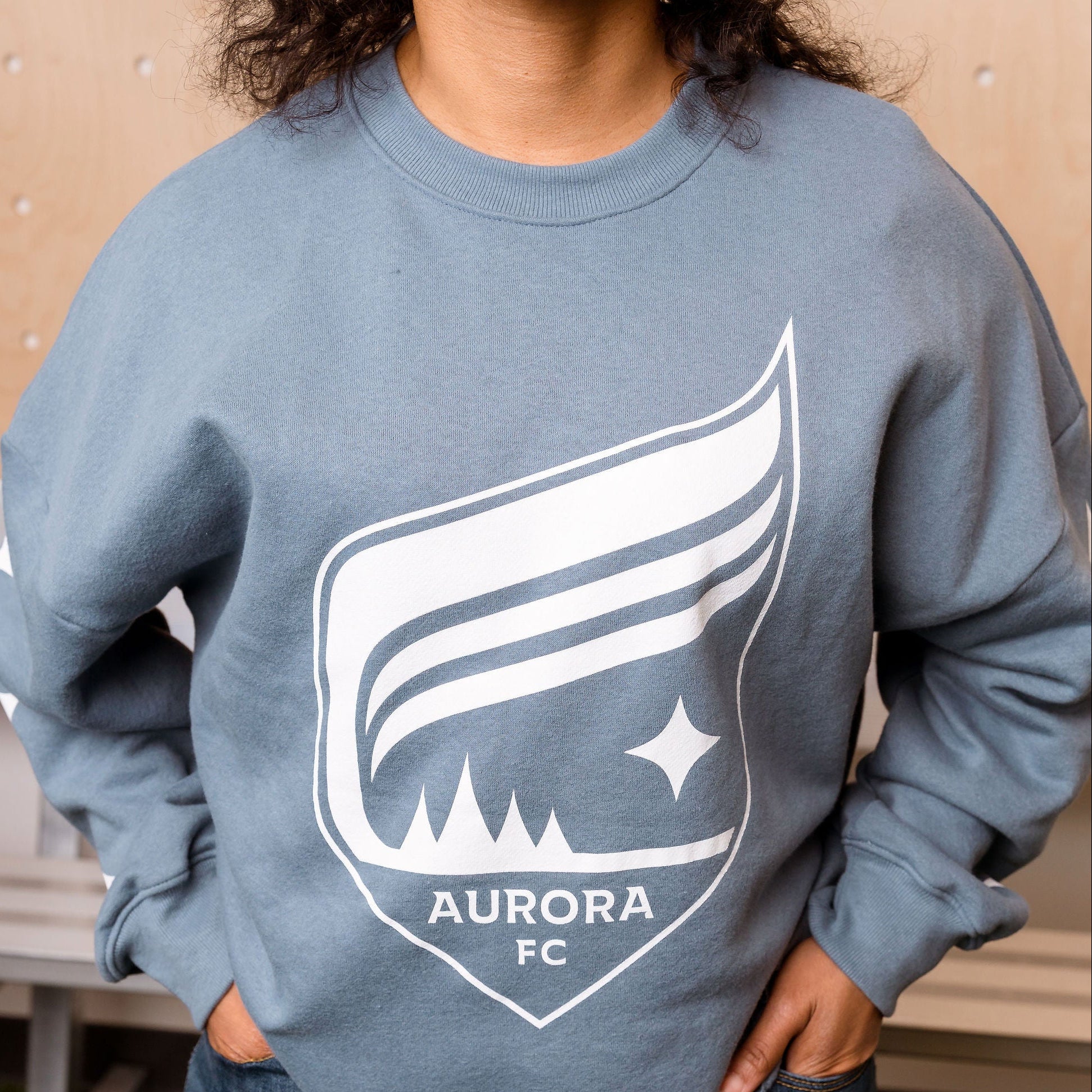 Person wearing a blue sweatshirt with Aurora FC logo