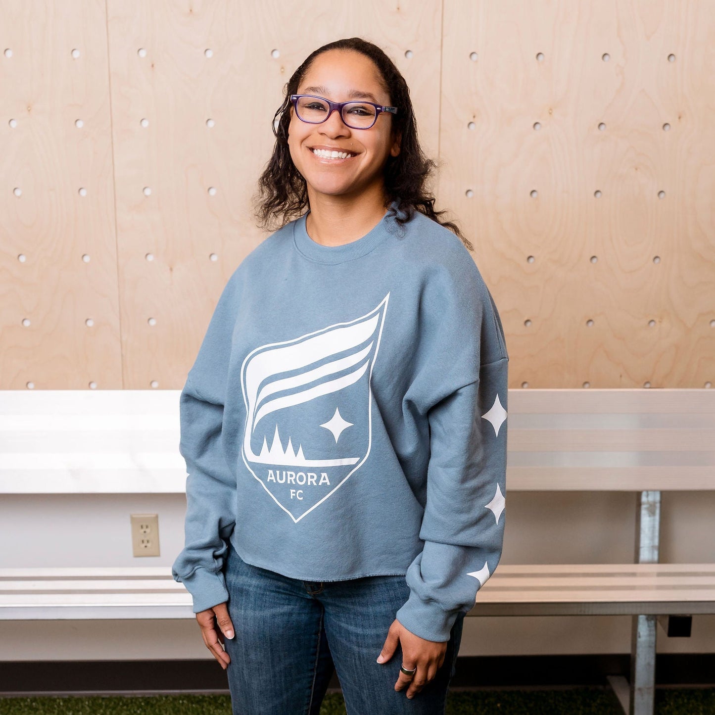 Person wearing a blue sweatshirt with a logo in an indoor setting