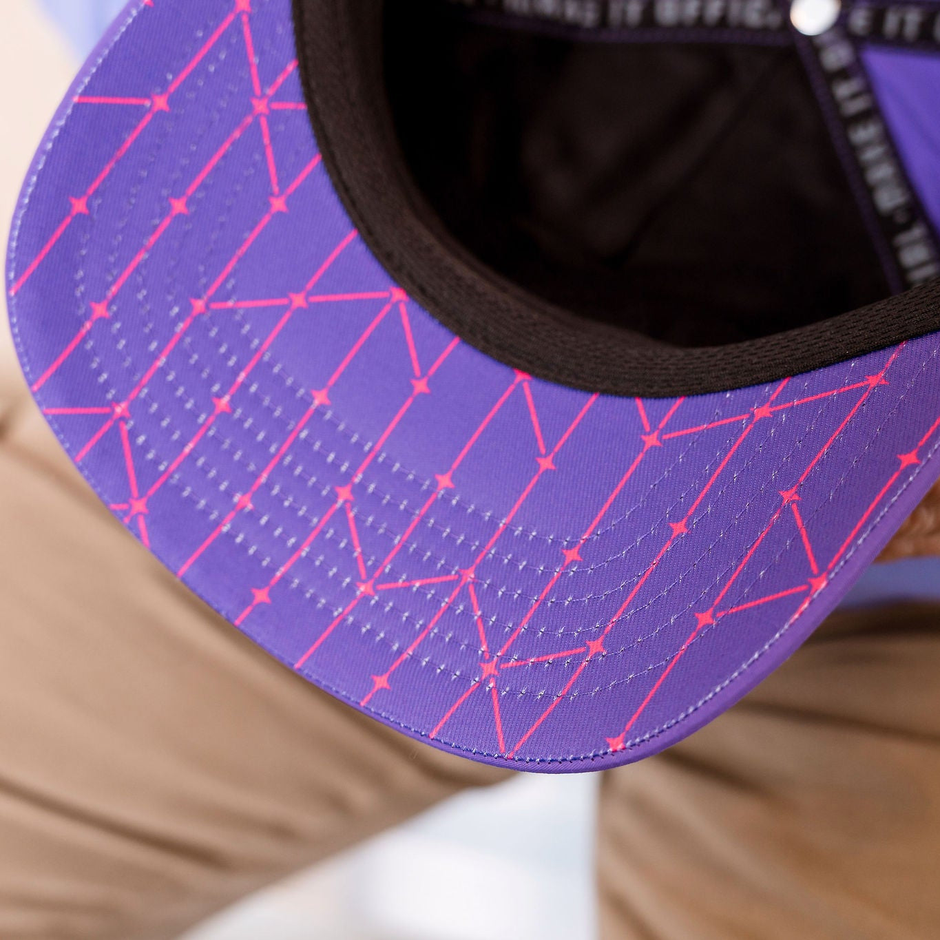 Purple cap with pink geometric pattern held by a person