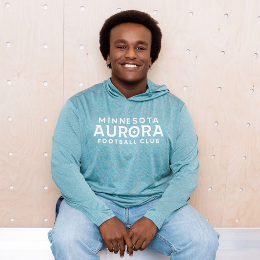Person wearing a teal hoodie with 'Minnesota Aurora' text, sitting on a white bench.