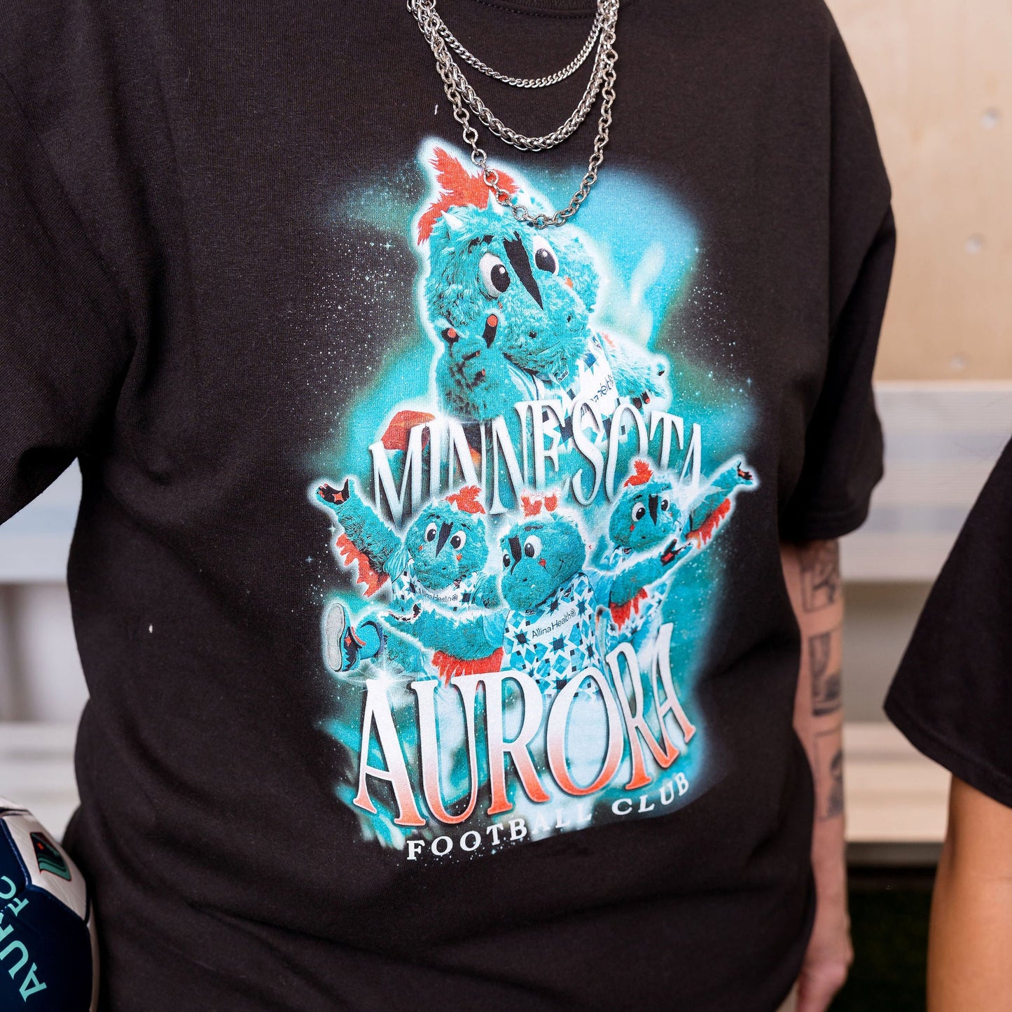 Person wearing a black t-shirt with a colorful graphic design of a bear and text.