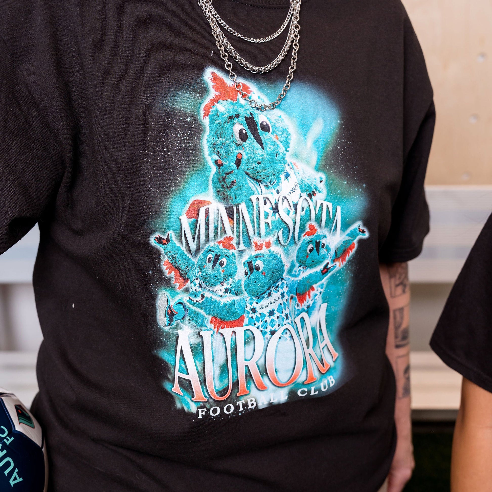 Person wearing a black t-shirt with a colorful graphic design of a bear and text.