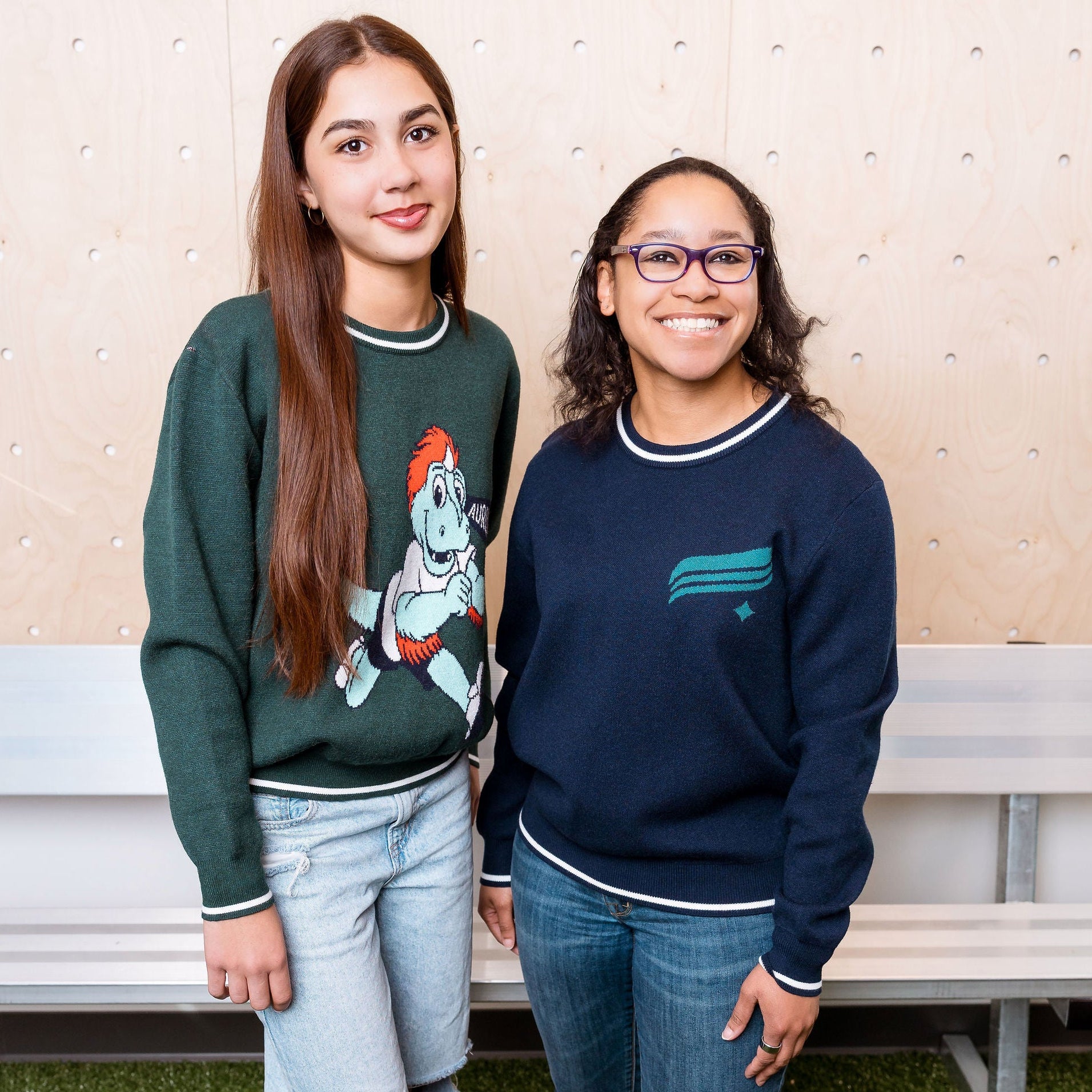 Two people standing next to each other in front of a wood wall.