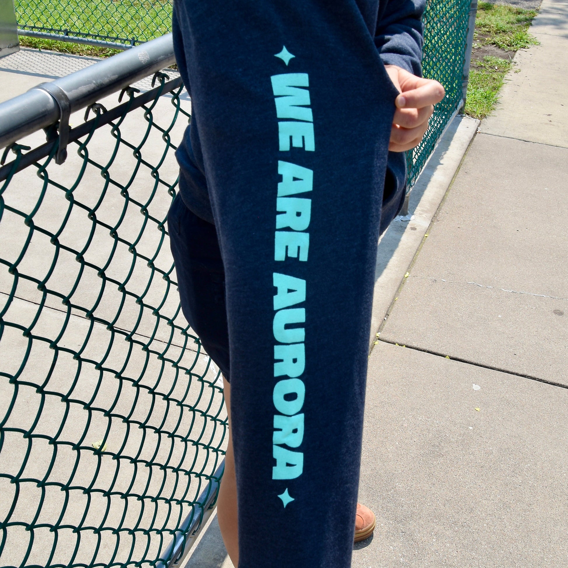 Person wearing navy sweatshirt with 'WE ARE AURORA' text.