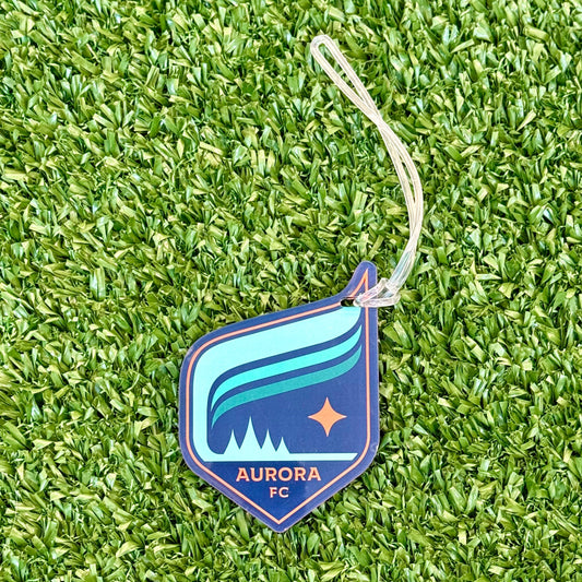 Plastic luggage tag with a clear string attached featuring the Aurora crest