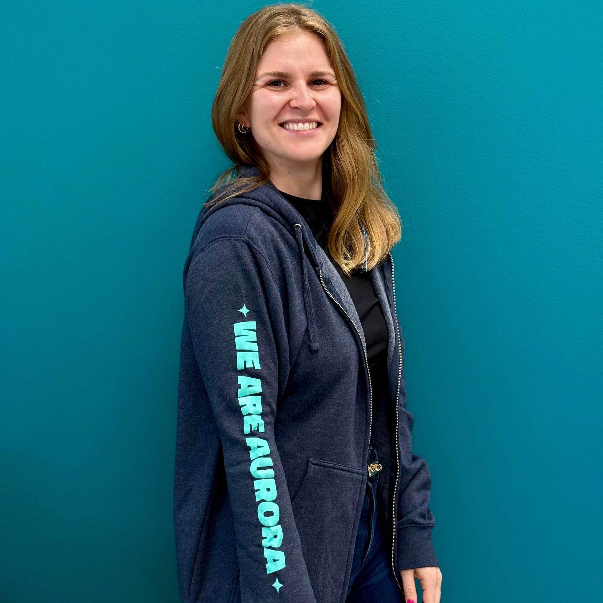 Navy blue full-zip with the words "WE ARE AURORA" in teal down the sleeve 