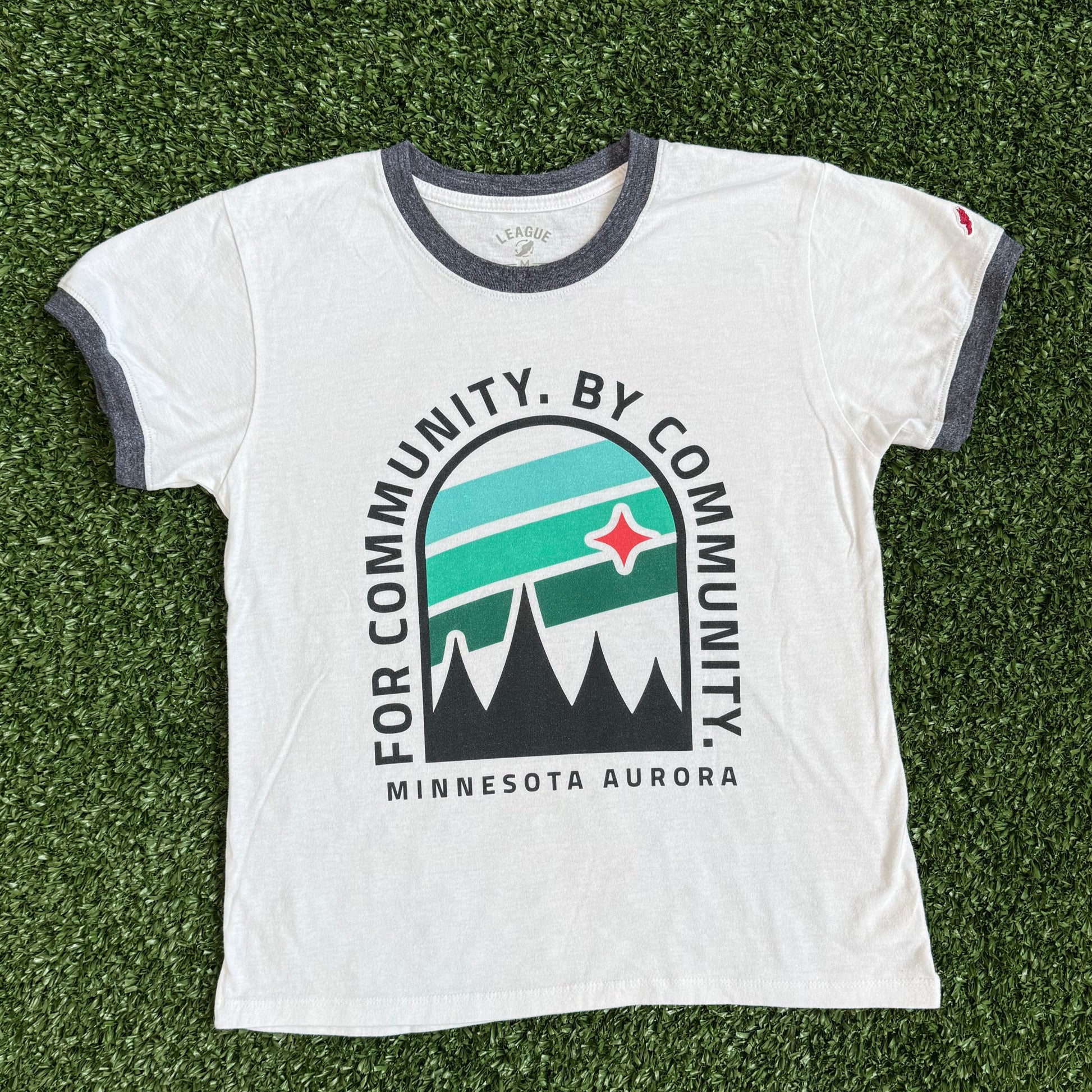 White t-shirt with a logo and text on a green grass-like surface