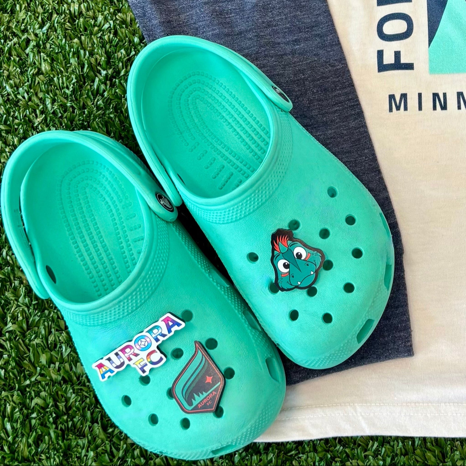 T-shirt with graphic design, teal shoes, and cap on grass