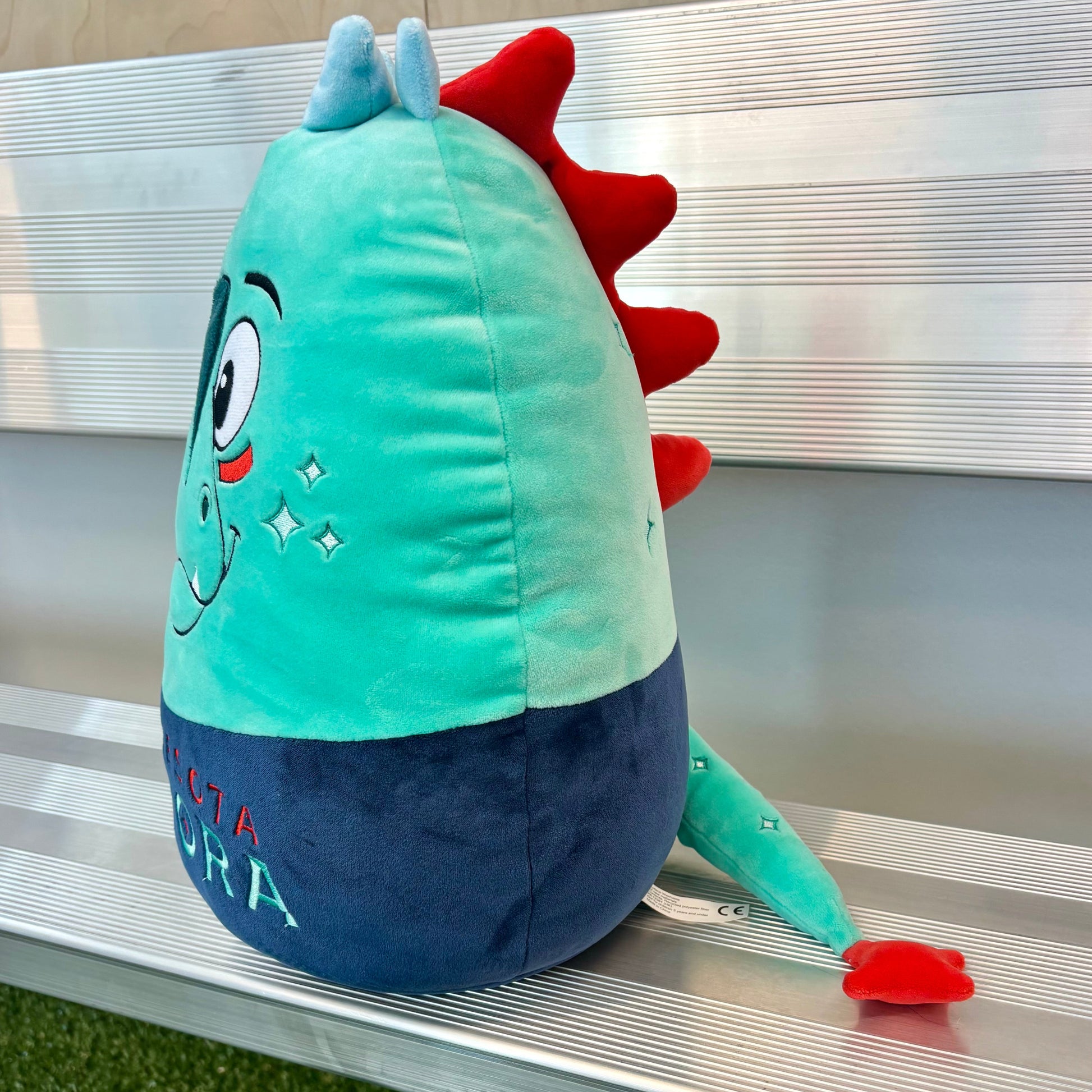 Plush Rory from the side on a metal bench.