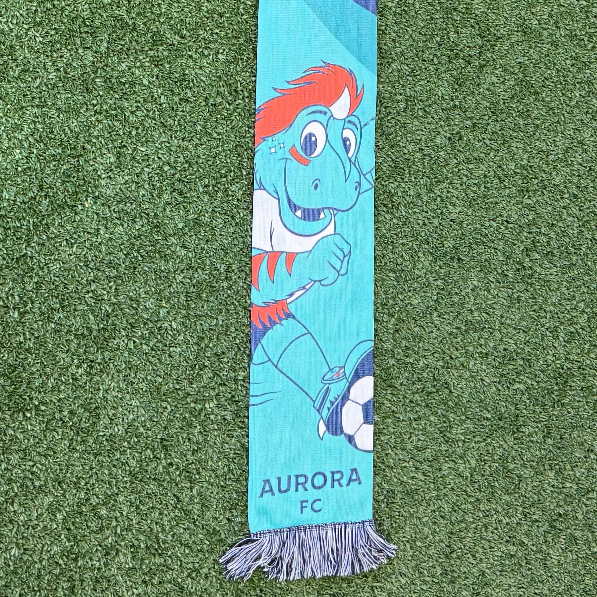 Scarf with 'Rory' printed on it on a green surface