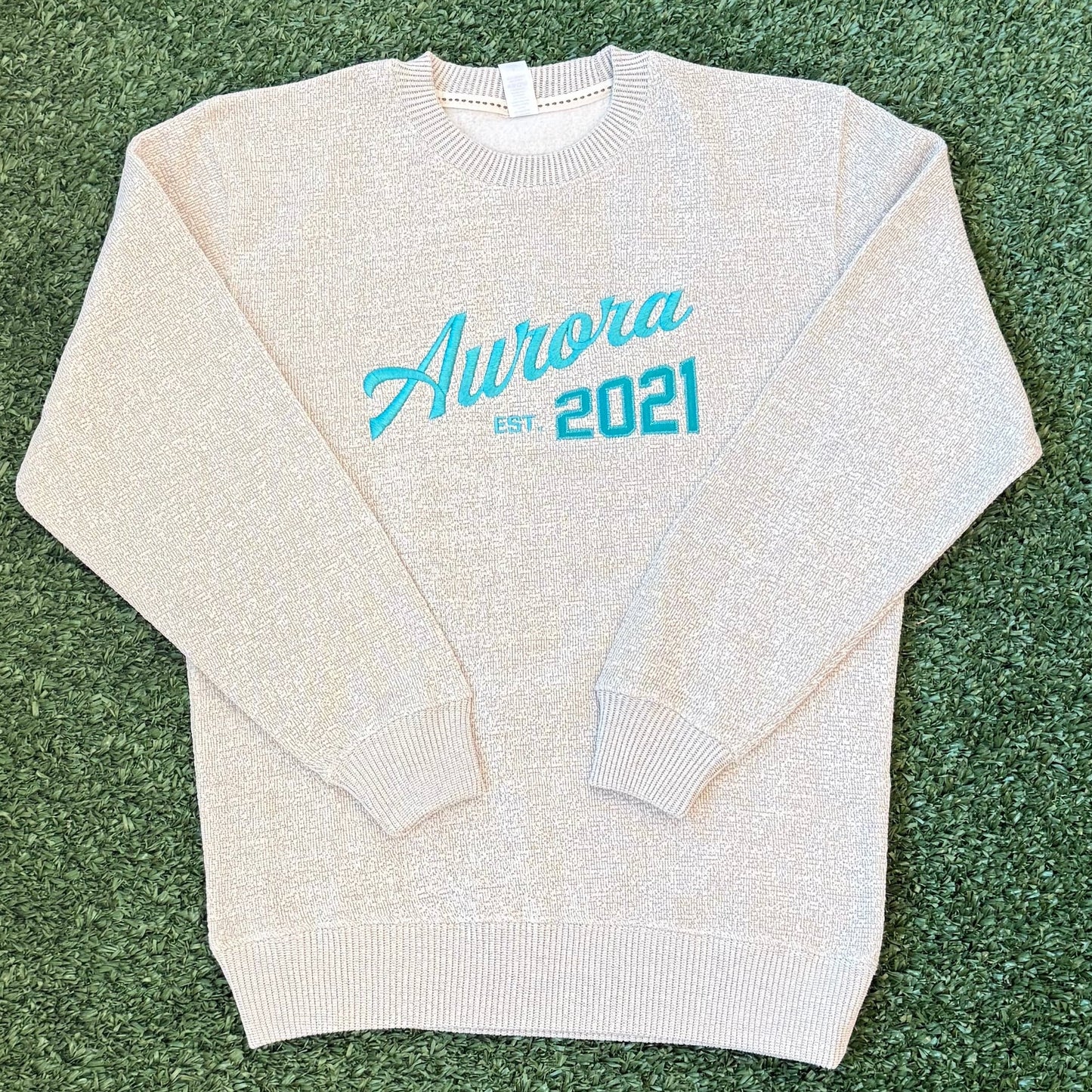 Folded ivory crewneck sweatshirt with teal text 