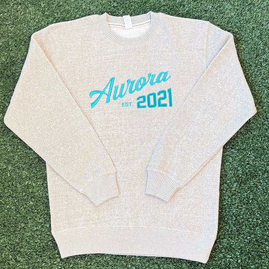 Folded ivory crewneck sweatshirt with teal text 