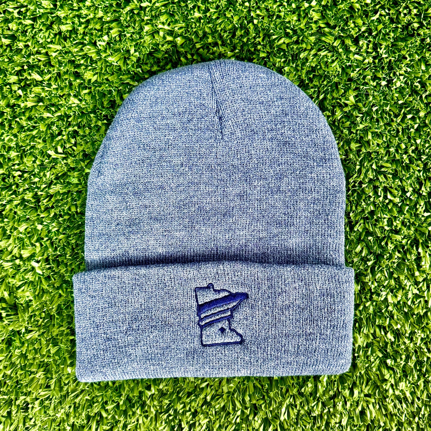 Blue beanie with a logo on a green grass background