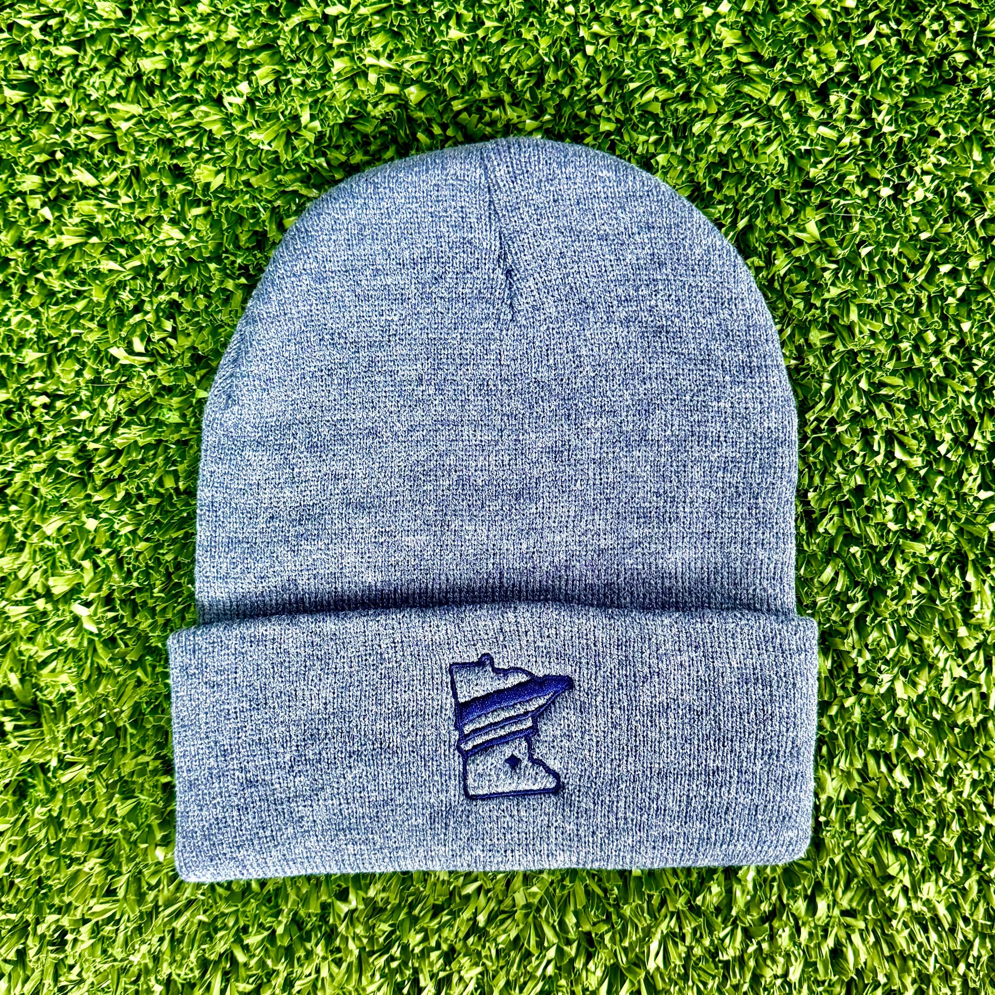 Blue beanie with a logo on a green grass background