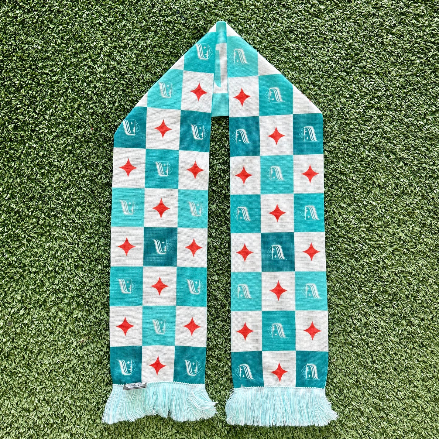 Checkered scarf with red and white pattern on a green grass background