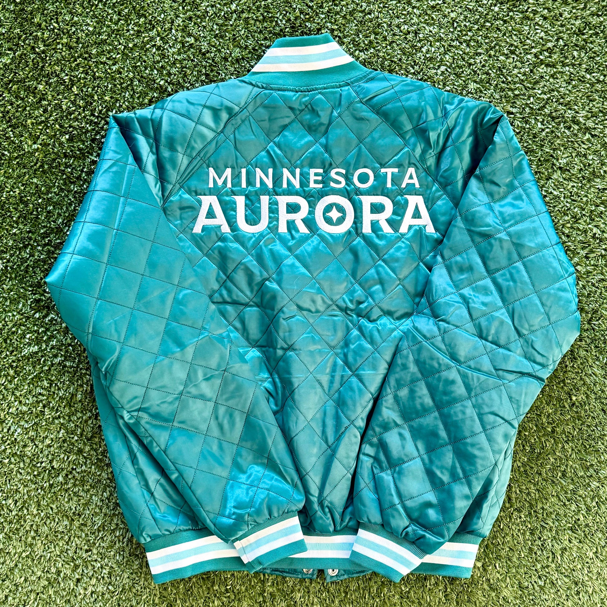 Teal jacket with 'Minnesota Aurora' text on a grassy background