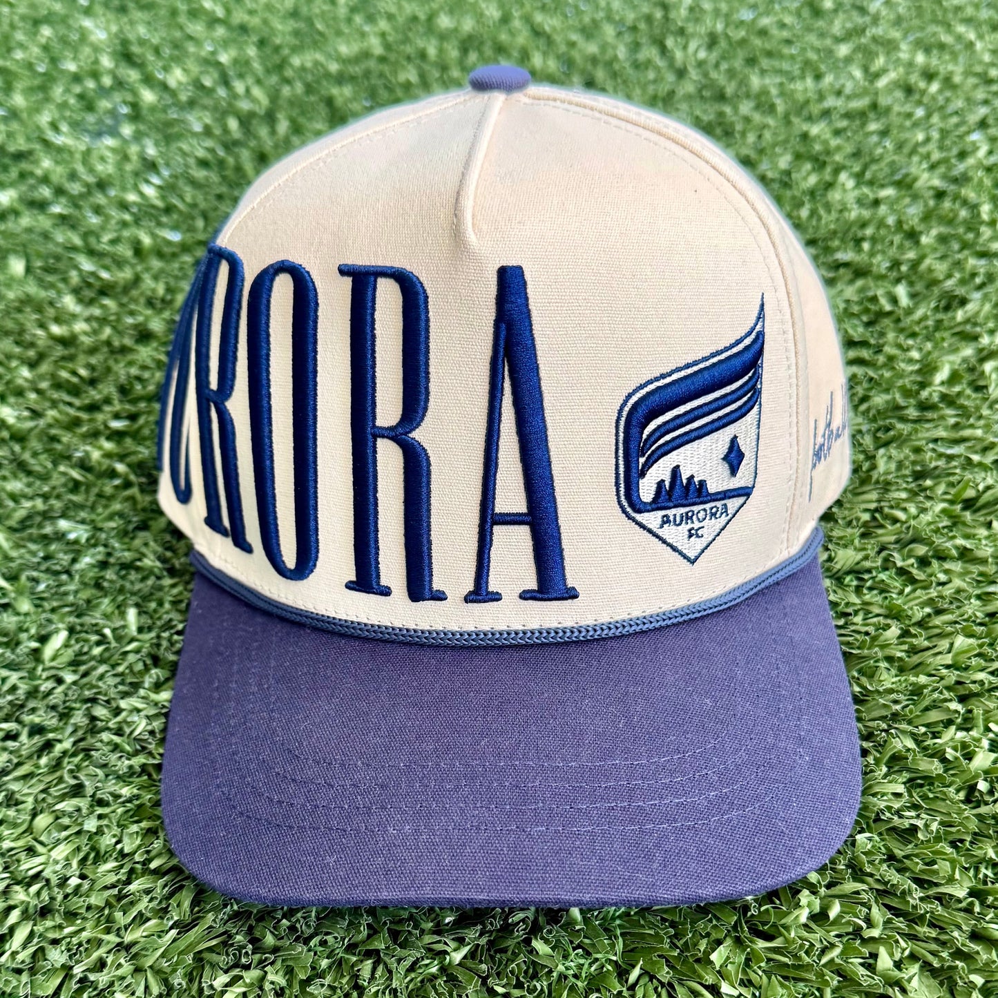 Cap with 'Aurora' branding on a grassy surface