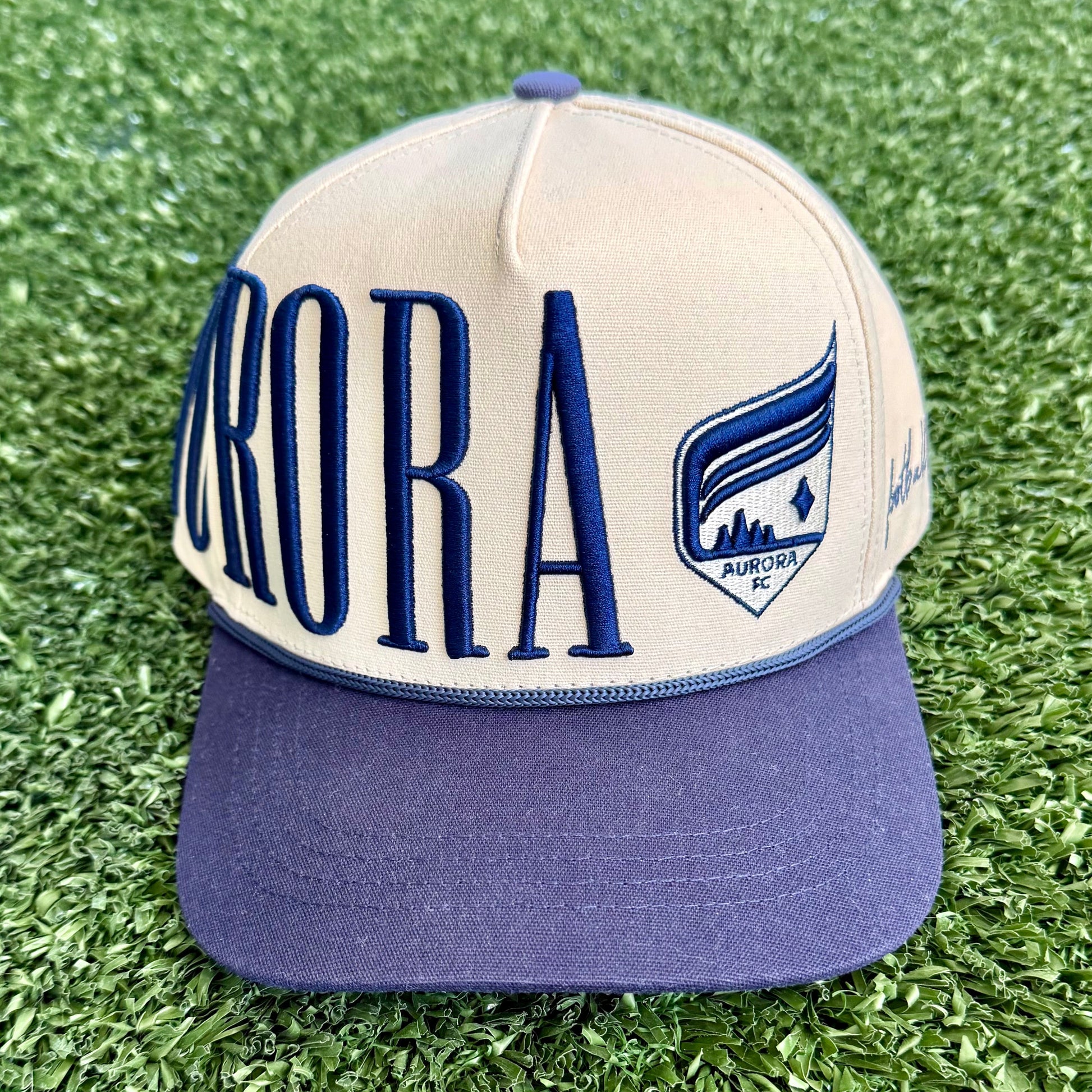 Cap with 'Aurora' branding on a grassy surface