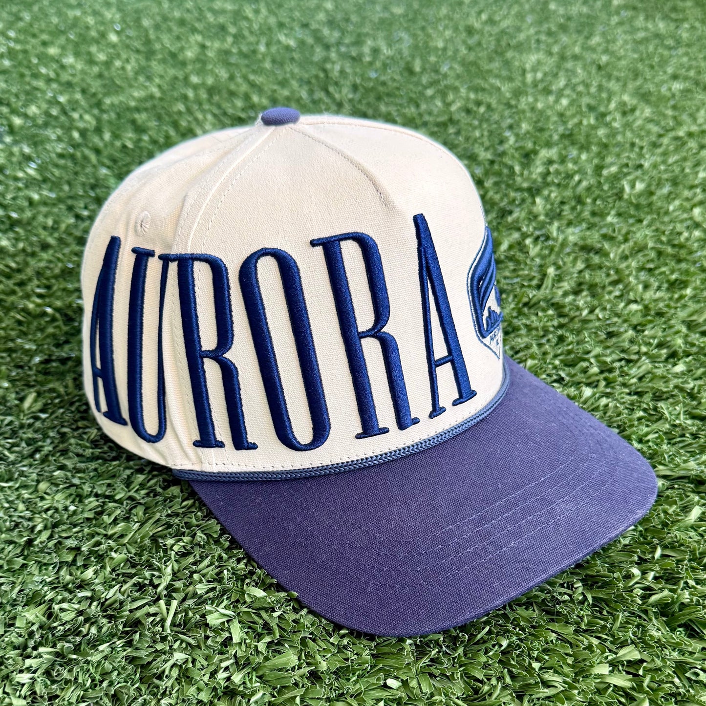Cap with 'AURORA' text on a green grass-like surface