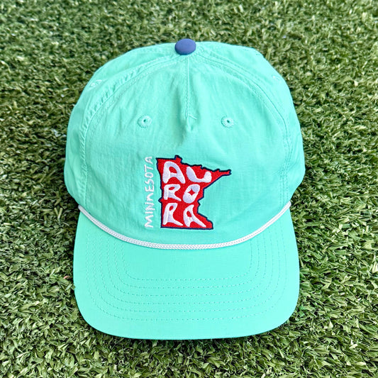 Light teal cap with a MN logo on a grassy background