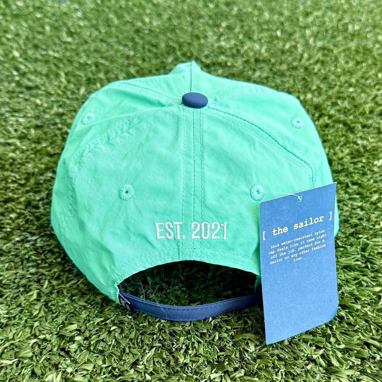 Teal cap with a blue tag on artificial grass